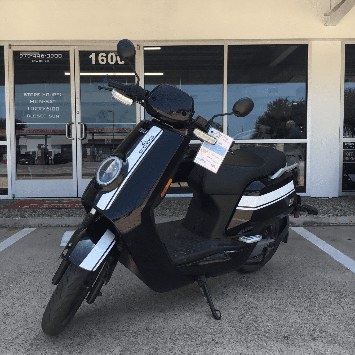 A black scooter parked in front of a store.