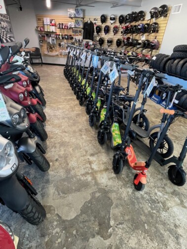 Row of scooters and helmets in showroom.